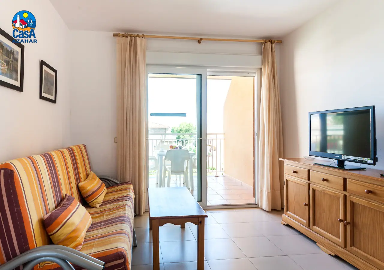 Séjour d'un appartement Bovalar avec canapé, télévision et accès à la terrasse