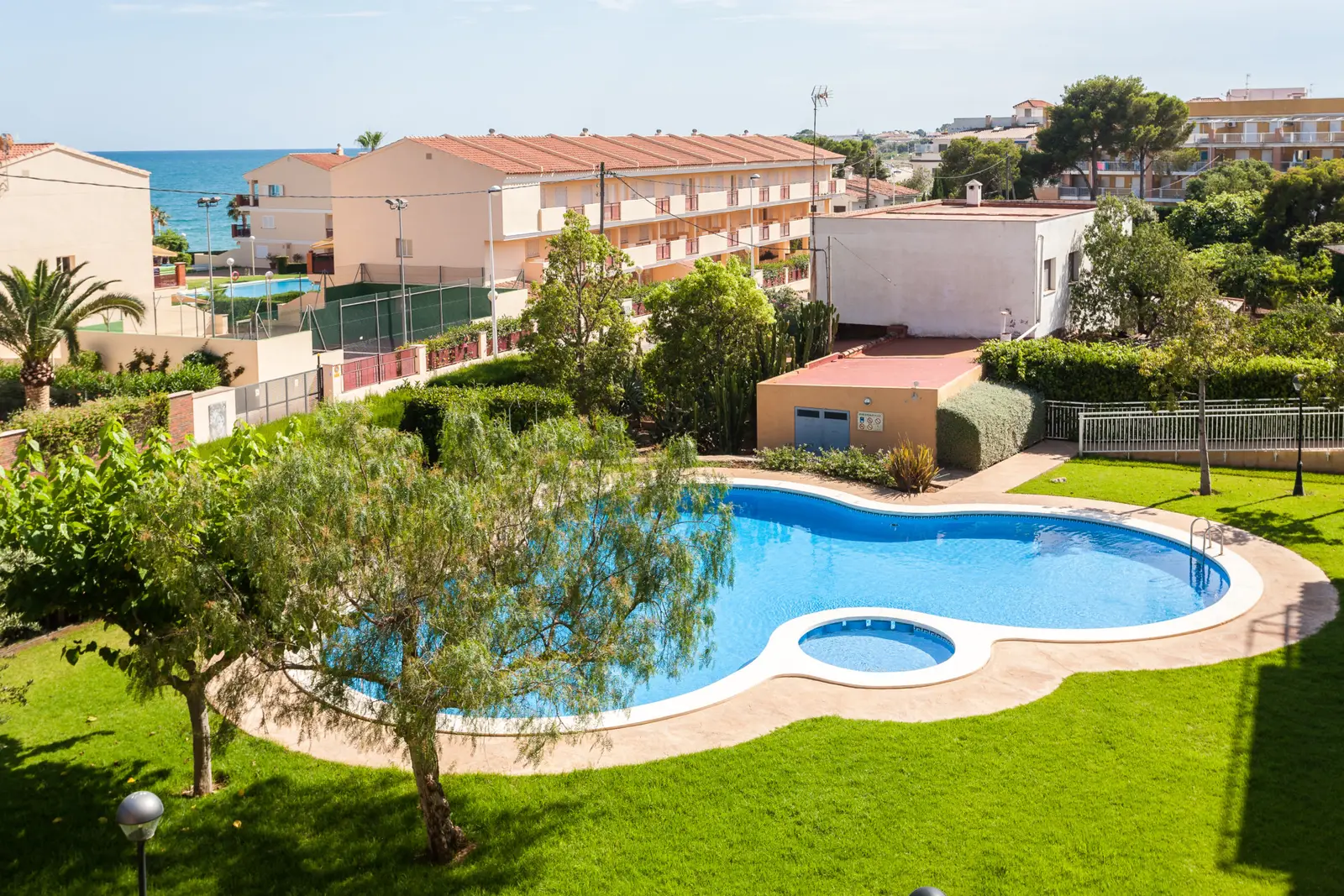 Vue sur le jardin et la piscine de Bovalar depuis un étage élevé, avec la mer au fond